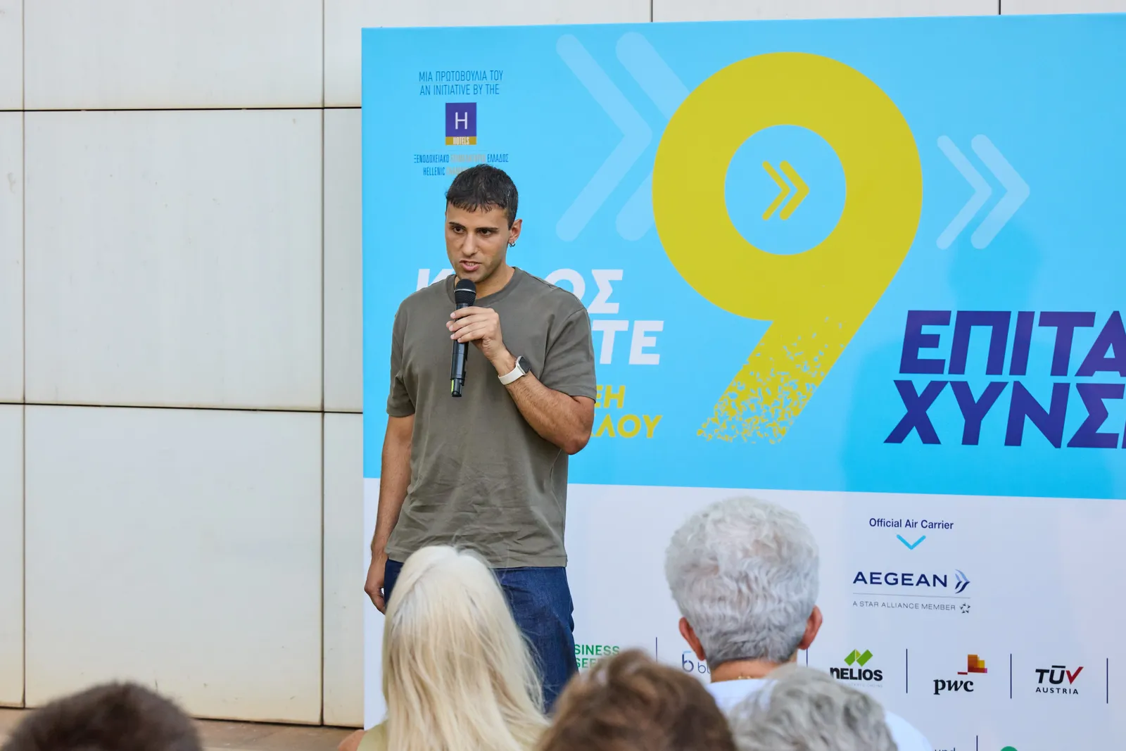 Een spreker richt zich tot het publiek voor de achtergrond van de 9e acceleratiecyclus
